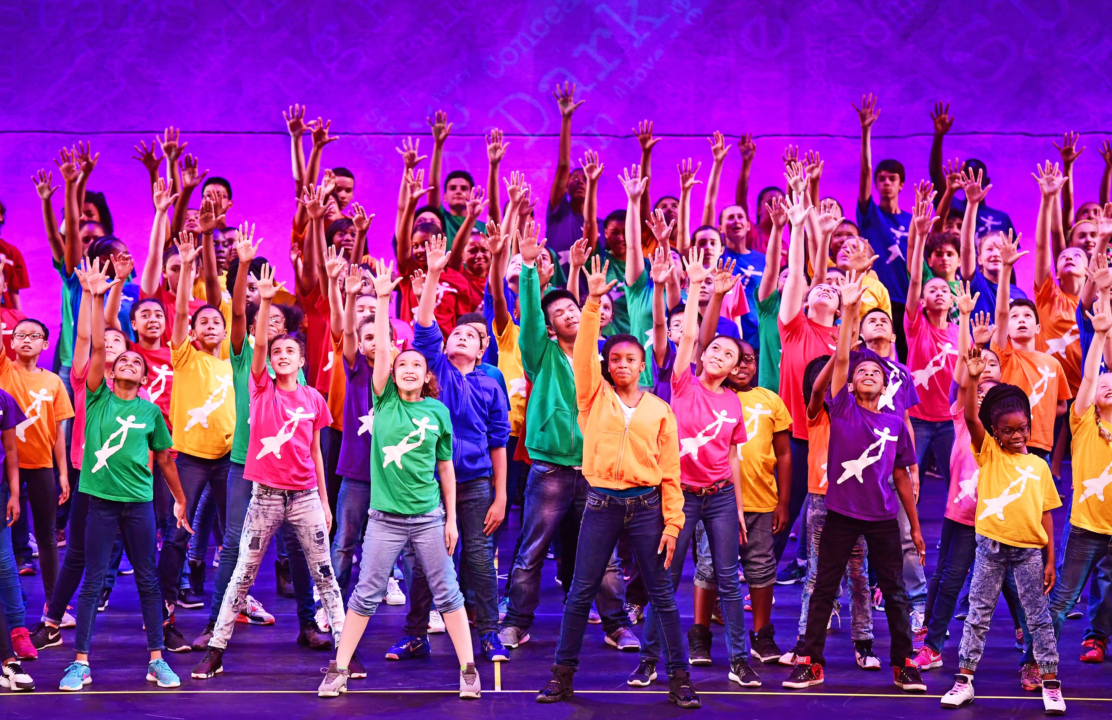 Children on stage with their arms in the air